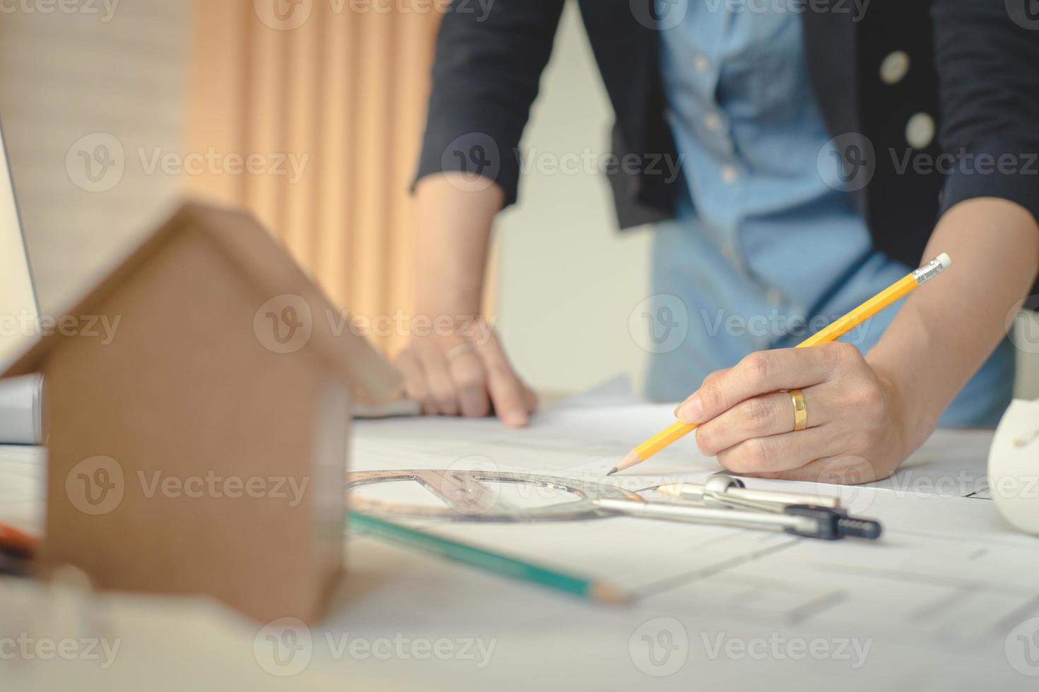 Hands of architect woman or engineer using pencil working with blueprint on desk in office. Engineering tools and construction concept. Architect and Business concept.Teamwork Concept.Vintage effect. photo