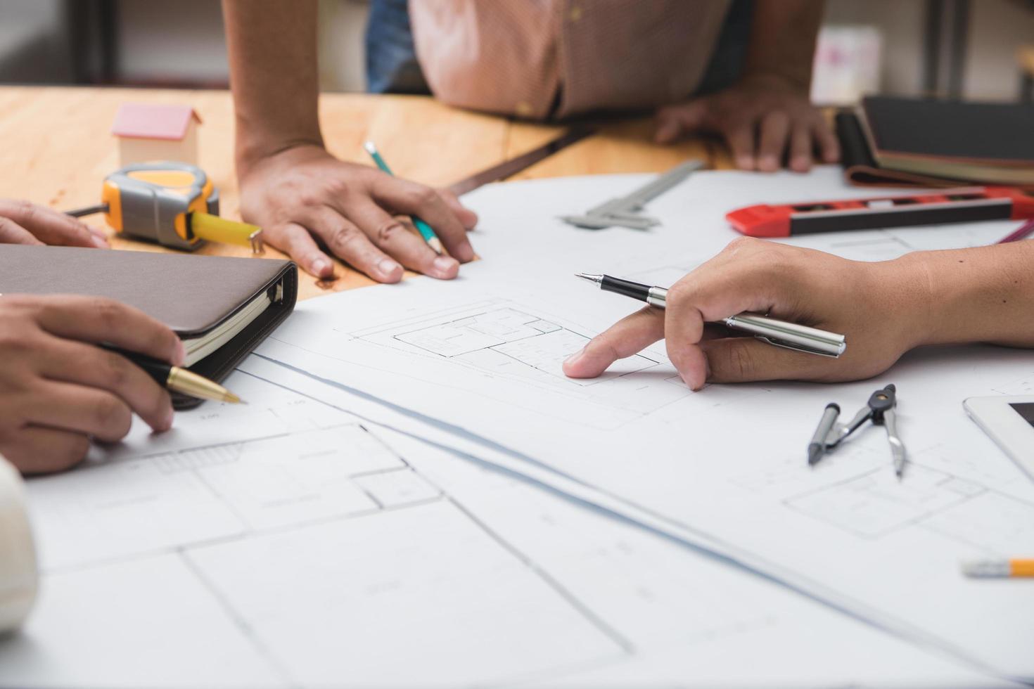 equipo de arquitectos o ingenieros discutiendo en el escritorio con planos sobre el nuevo proyecto de inicio en el escritorio. grupo de equipo en los documentos de verificación del sitio de construcción y el flujo de trabajo comercial. enfoque selectivo. foto