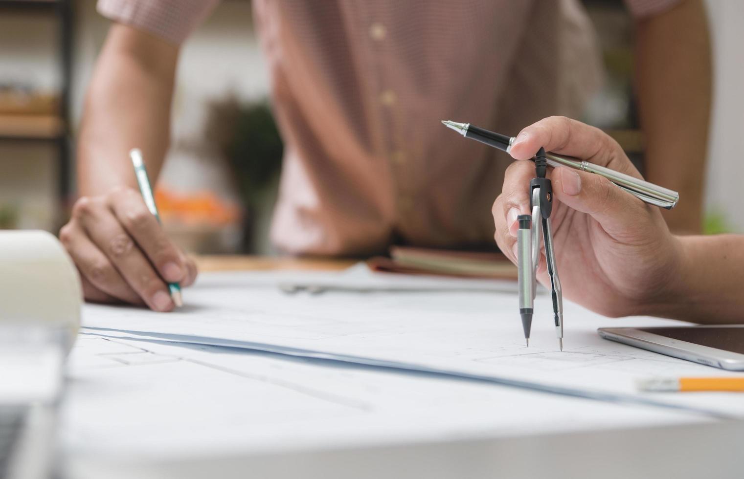 manos de arquitecto o ingeniero usando lápiz trabajando con planos en el escritorio en la oficina. herramientas de ingeniería y concepto de construcción. concepto de arquitecto y negocio. enfoque selectivo, efecto vintage. foto