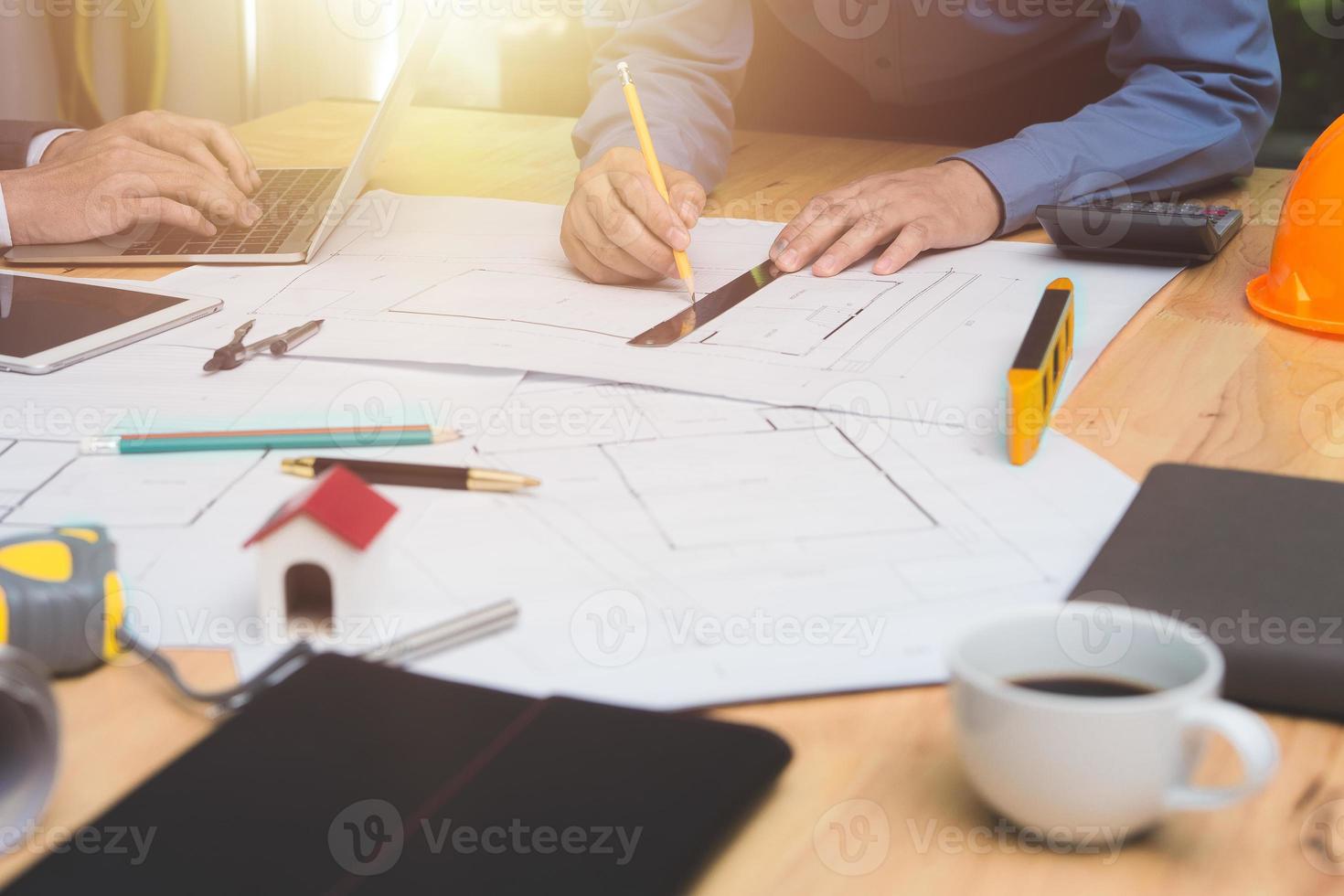 equipo de arquitectos o ingenieros discutiendo en el escritorio con planos sobre el nuevo proyecto de inicio en el escritorio. grupo de equipo en los documentos de verificación del sitio de construcción y el flujo de trabajo comercial. enfoque selectivo. foto