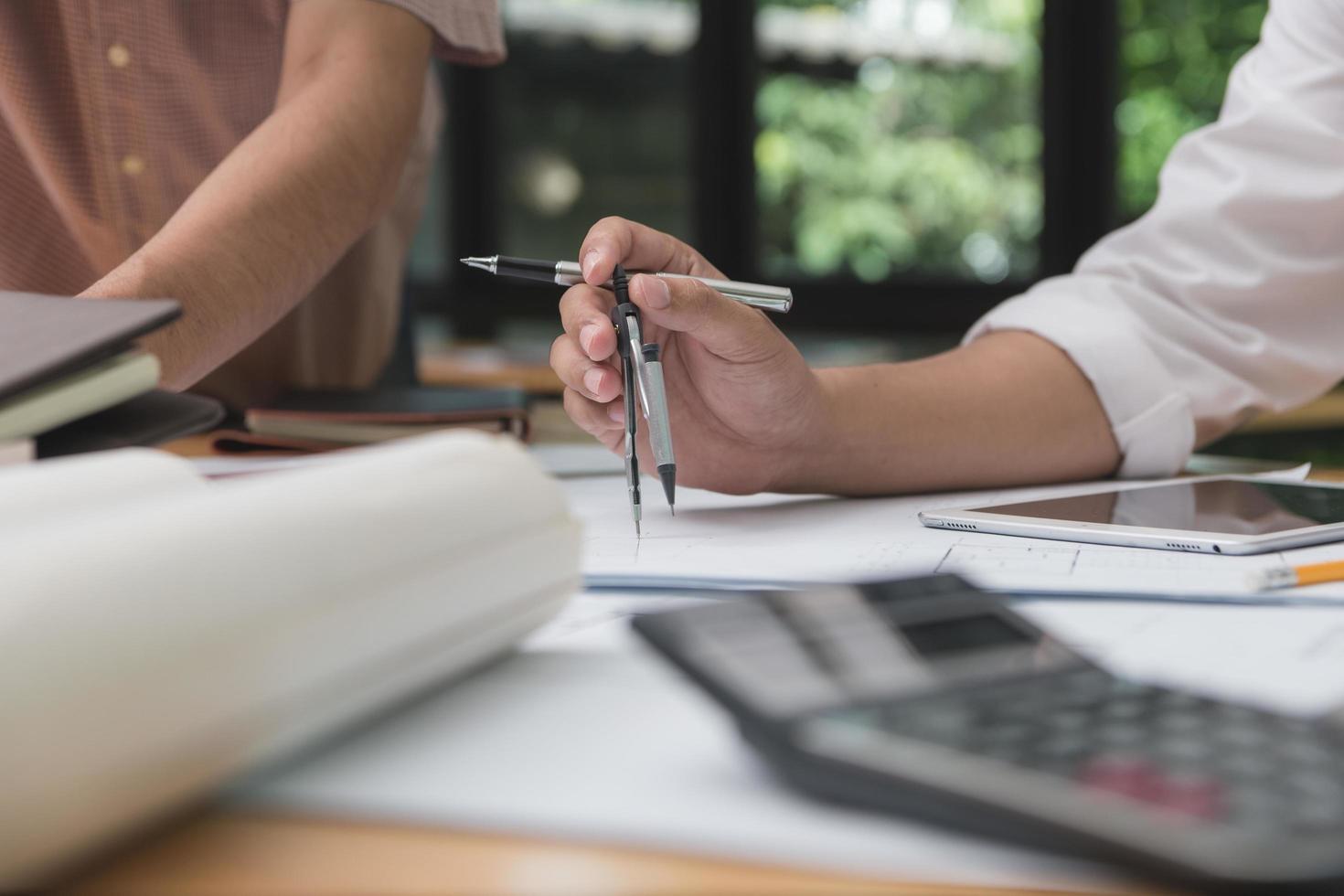 equipo de arquitectos o ingenieros discutiendo en el escritorio con planos sobre el nuevo proyecto de inicio en el escritorio. grupo de equipo en los documentos de verificación del sitio de construcción y el flujo de trabajo comercial. enfoque selectivo. foto