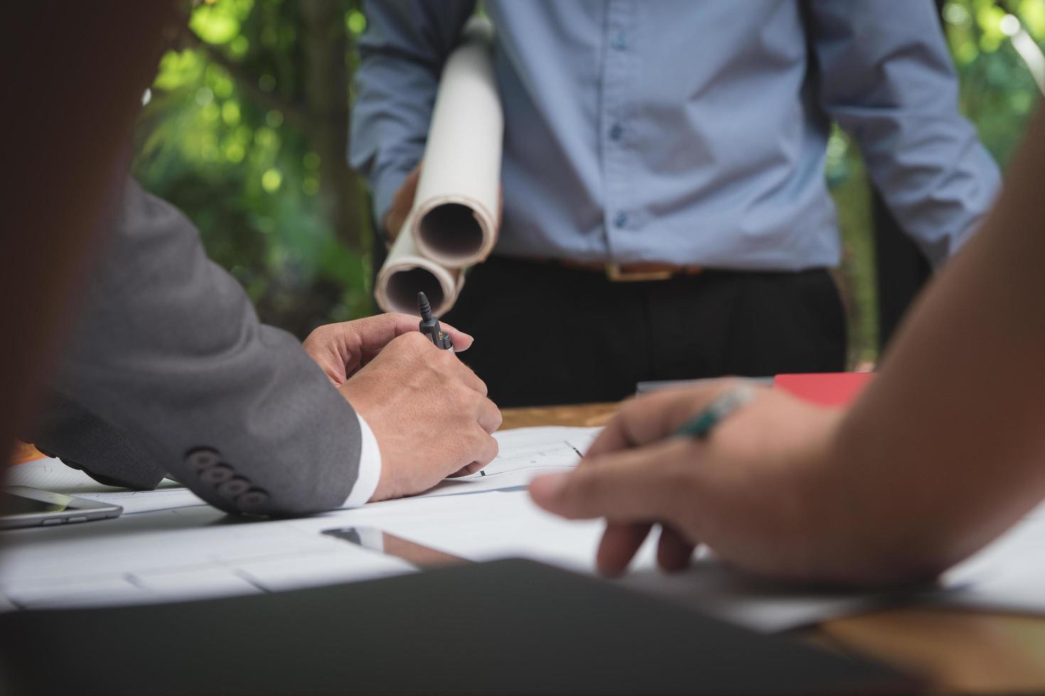 equipo de arquitectos o ingenieros discutiendo en el escritorio con planos sobre el nuevo proyecto de inicio en el escritorio. grupo de equipo en los documentos de verificación del sitio de construcción y el flujo de trabajo comercial. enfoque selectivo. foto