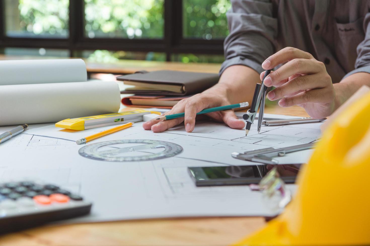 equipo de arquitectos o ingenieros discutiendo en el escritorio con planos sobre el nuevo proyecto de inicio en el escritorio. grupo de equipo en los documentos de verificación del sitio de construcción y el flujo de trabajo comercial. enfoque selectivo. foto