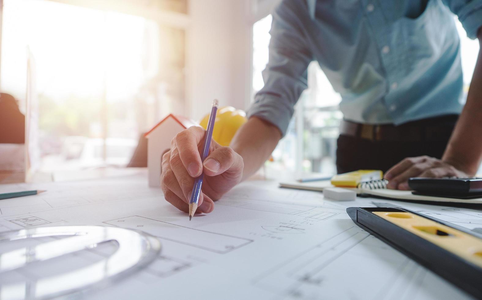 Hands of architect or engineer using drawing compass with blueprint on desk in office.Team of architects engineer discussing and check documents and business workflow.Construction concept. photo