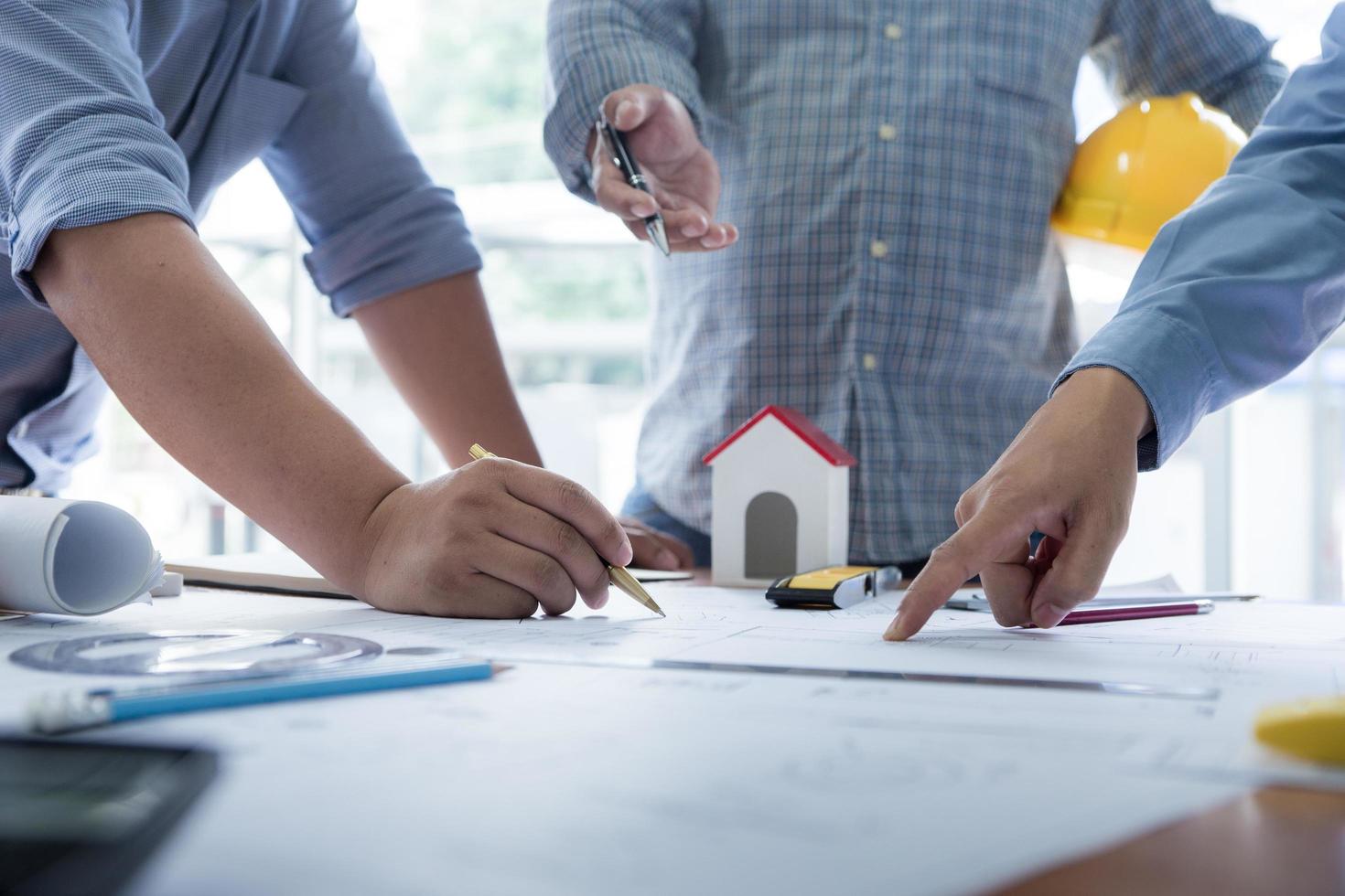 equipo de arquitectos o ingenieros discutiendo en el escritorio con planos sobre el nuevo proyecto de inicio en el escritorio. grupo de equipo en los documentos de verificación del sitio de construcción y el flujo de trabajo comercial. enfoque selectivo. foto