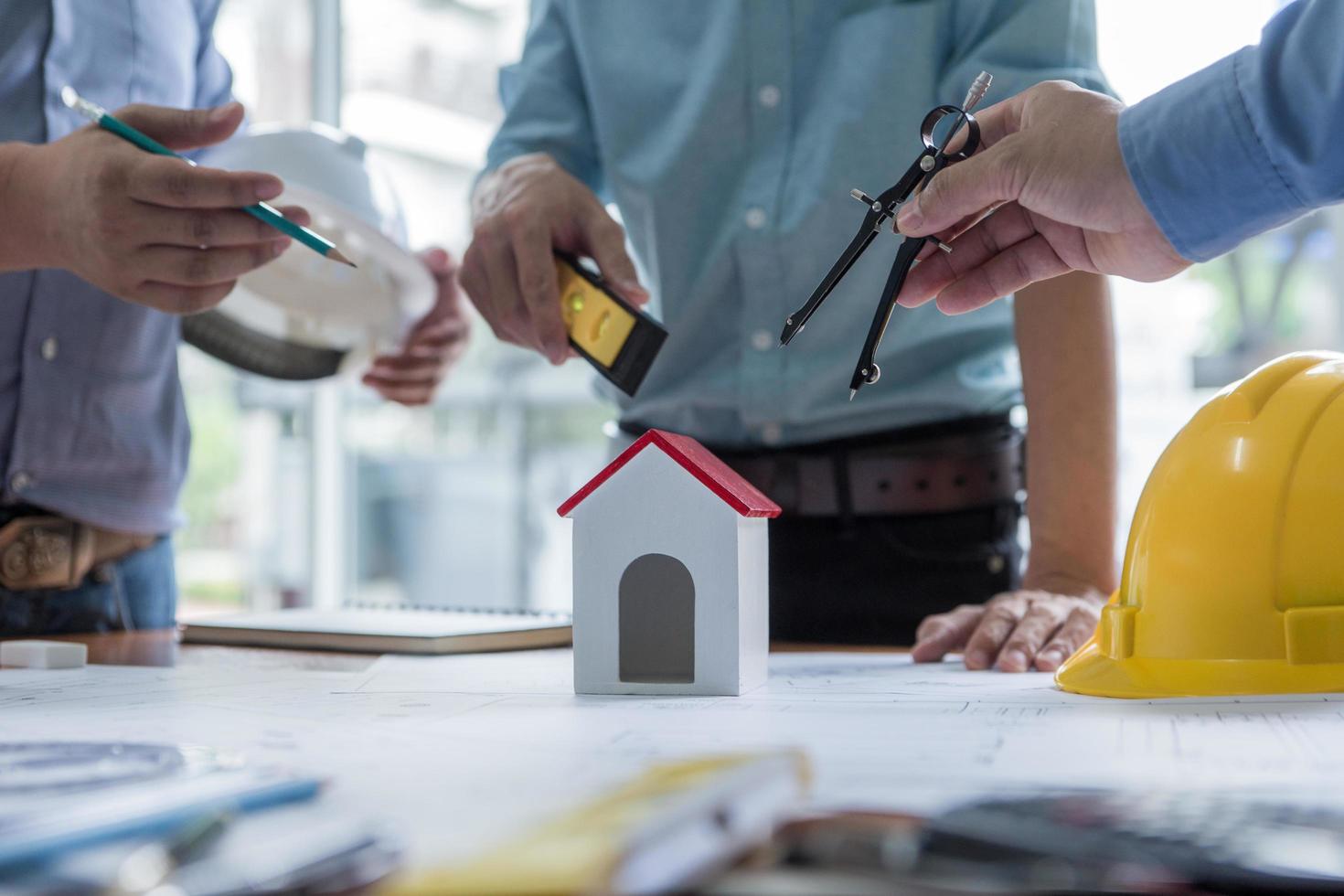 equipo de arquitectos o ingenieros discutiendo en el escritorio con planos sobre el nuevo proyecto de inicio en el escritorio. grupo de equipo en los documentos de verificación del sitio de construcción y el flujo de trabajo comercial. enfoque selectivo. foto