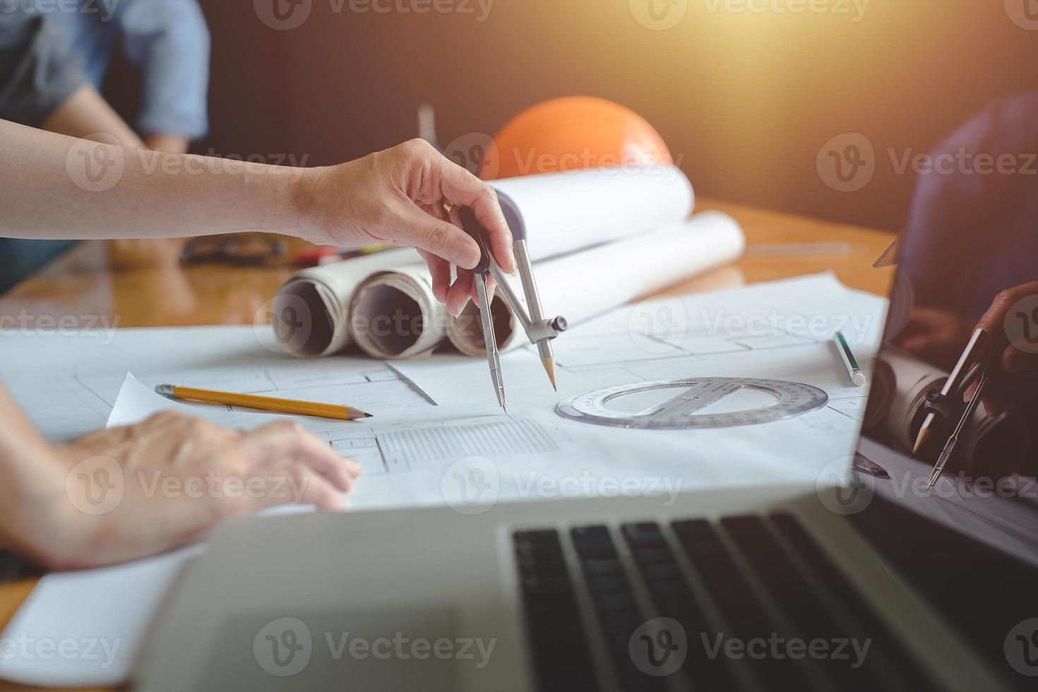 manos de arquitecto o ingeniero usando brújula de dibujo con plano en el escritorio en la oficina. equipo de arquitectos ingenieros discutiendo y verificando documentos y flujo de trabajo empresarial. concepto de construcción. foto