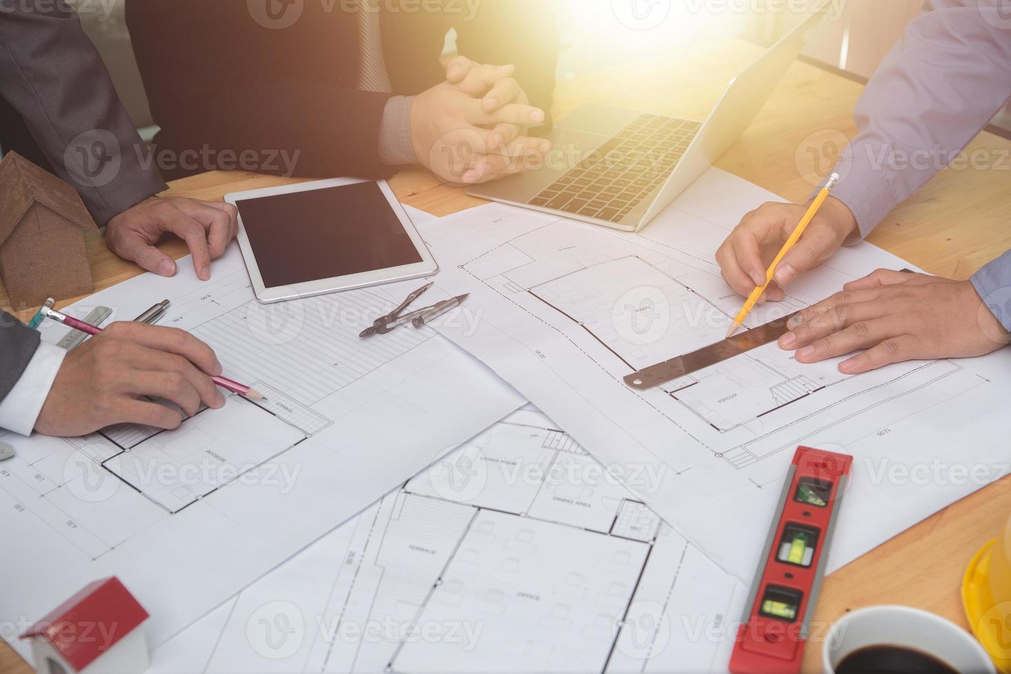 equipo de arquitectos o ingenieros discutiendo en el escritorio con planos sobre el nuevo proyecto de inicio en el escritorio. grupo de equipo en los documentos de verificación del sitio de construcción y el flujo de trabajo comercial. enfoque selectivo. foto