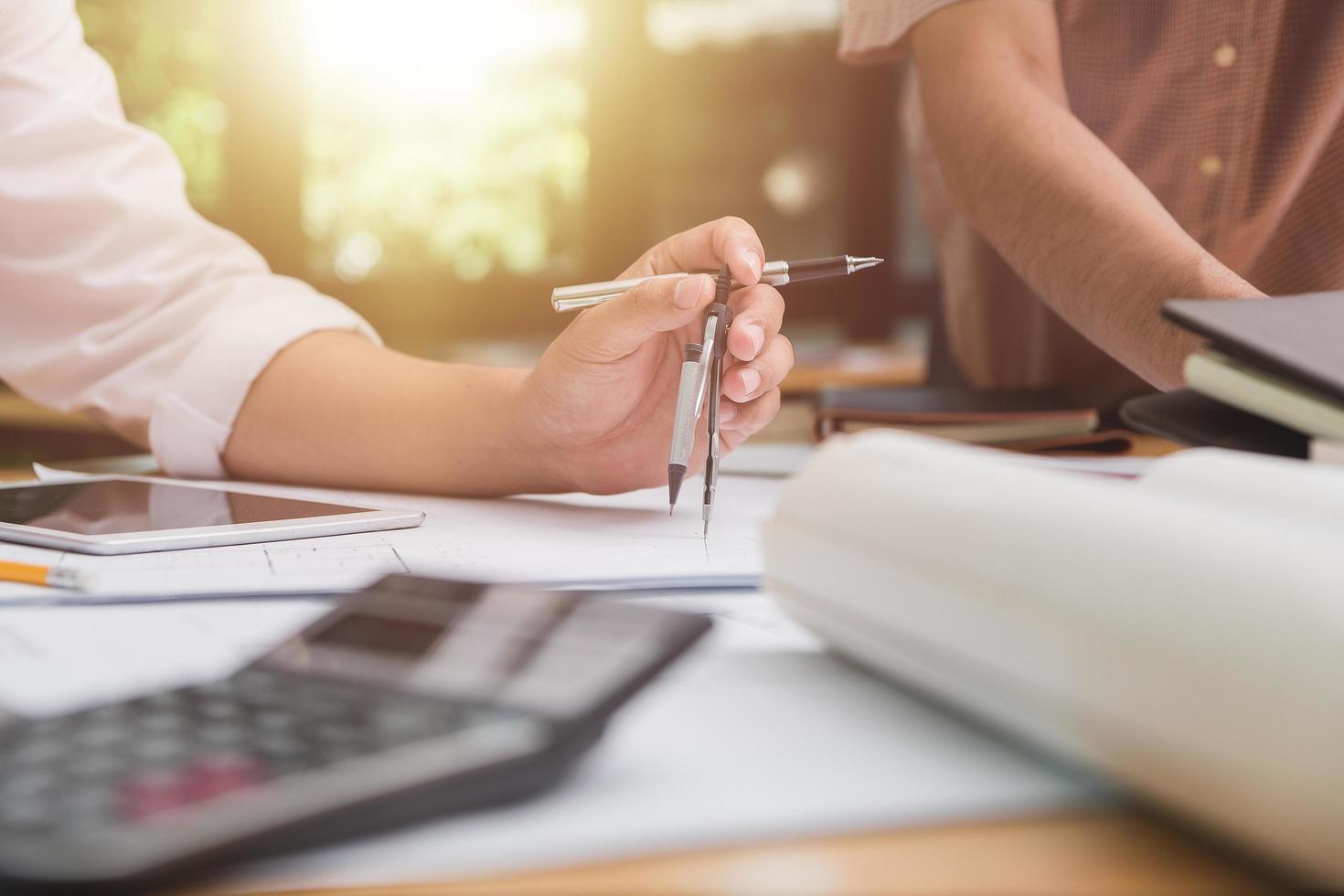 manos de arquitecto o ingeniero usando brújula de dibujo con plano en el escritorio en la oficina. equipo de arquitectos ingenieros discutiendo y verificando documentos y flujo de trabajo empresarial. concepto de construcción. foto