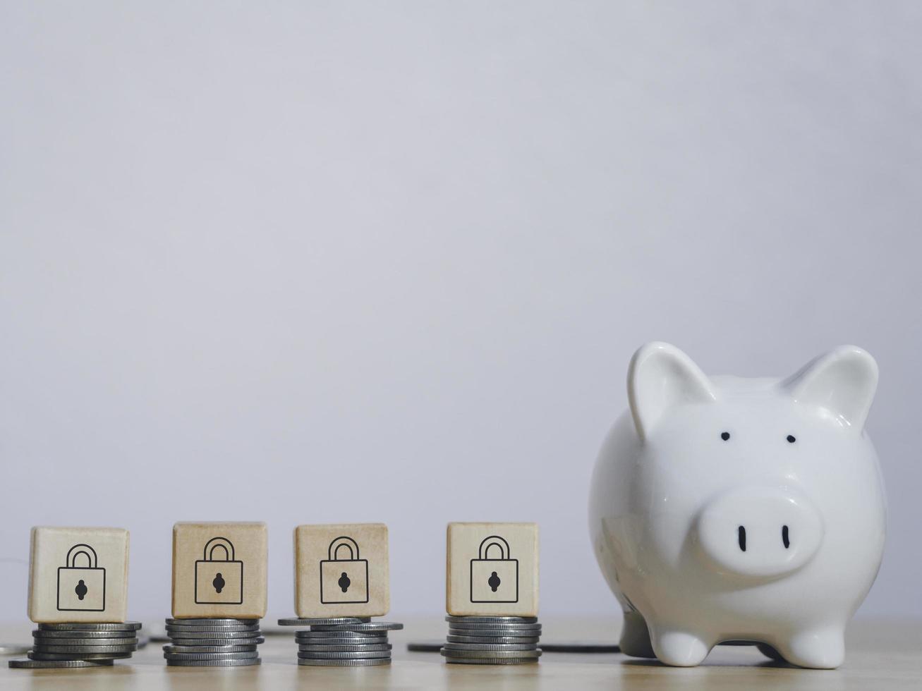 White piggy bank near stack coins with wooden padlock block on top on table to security of money invest for future. Concept for loan, property ladder, financial,real estate investment,taxes and bonus. photo