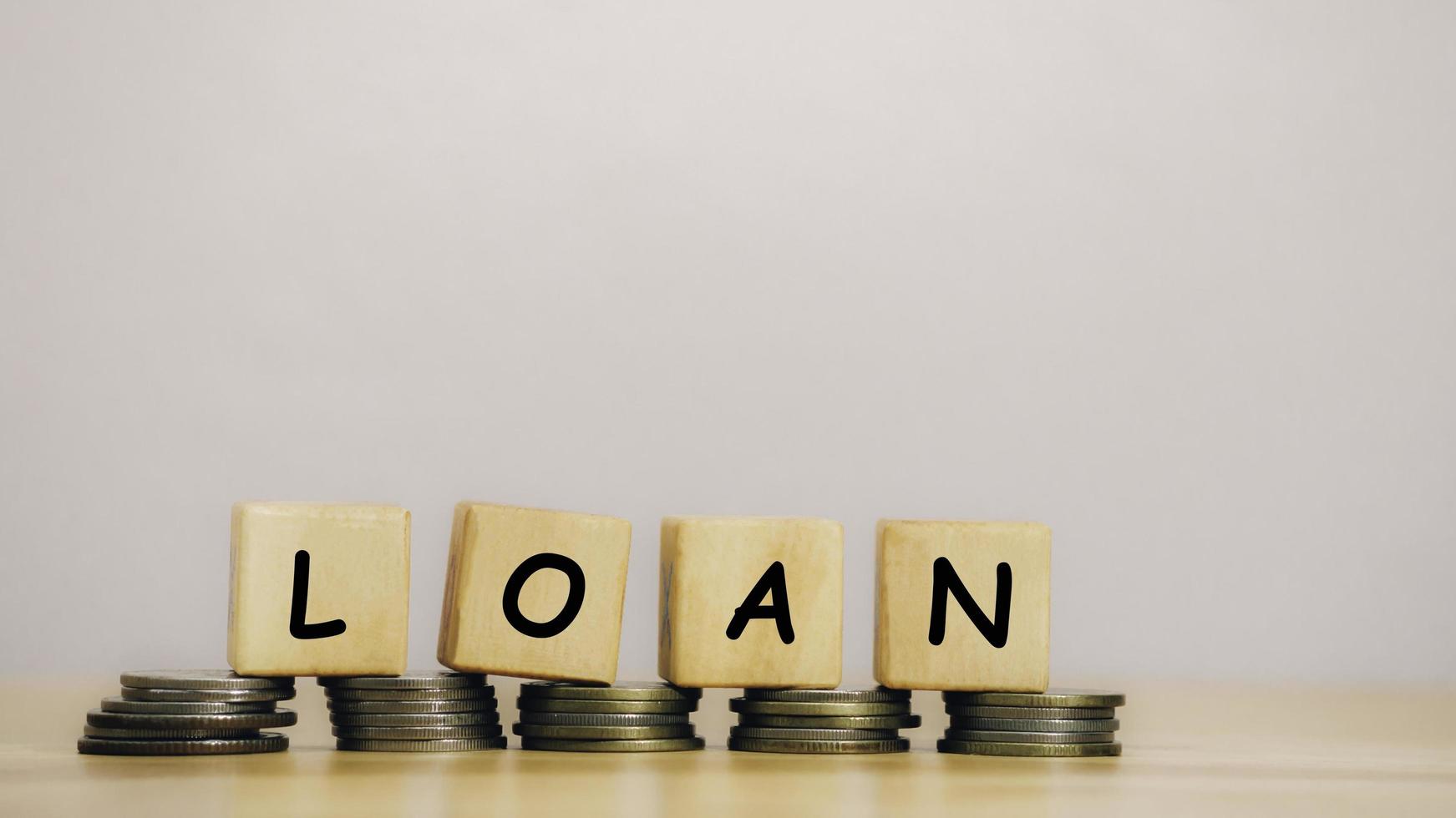 Close Up wooden block written LOAN against on stack coins to business and finance concept. Fees and Interest from loans are main revenue for banks. Loans can be unsecured such as credit card. photo
