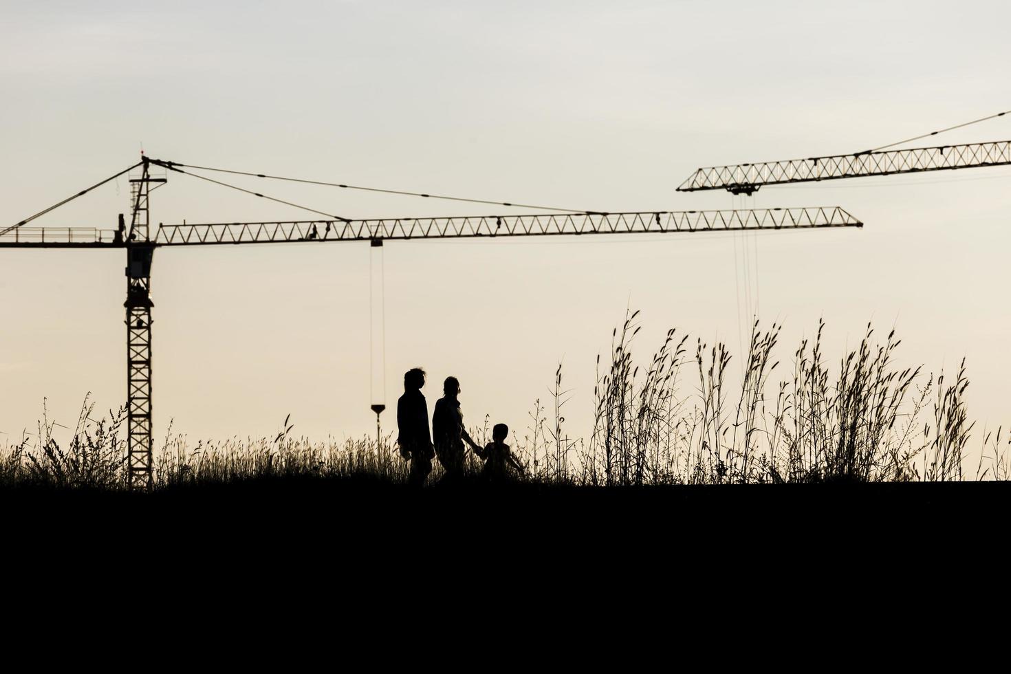 grúas de construcción industrial y siluetas de edificios sobre el sol al amanecer foto