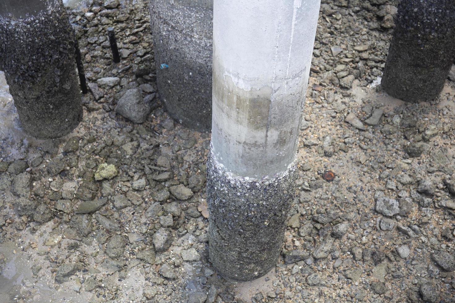 A cement pole by the sea that was eroded by the water. photo