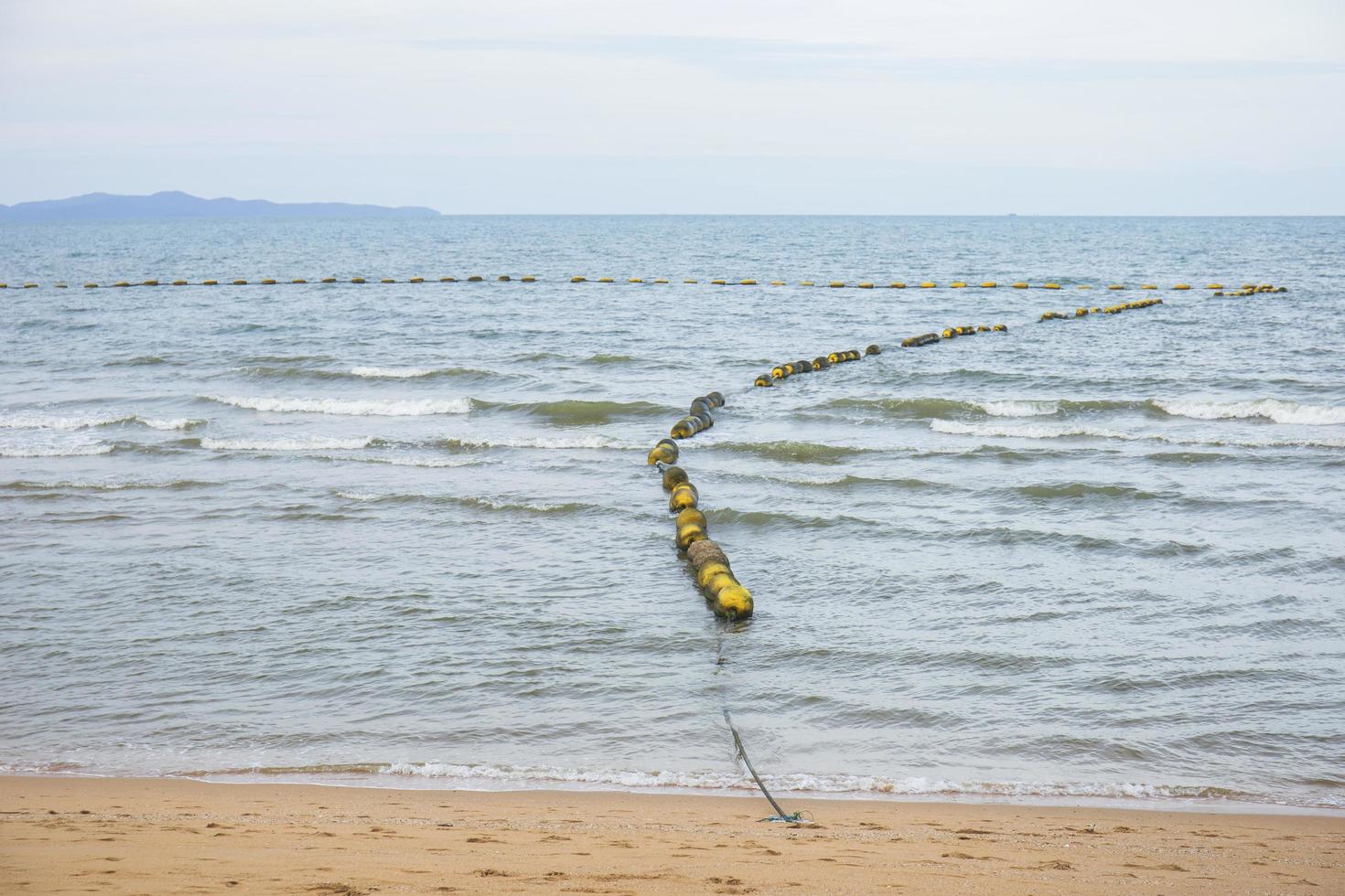 Vertical seascape with floating buoys and rope dividing area on the beach. Seacoast on a sunny day. photo
