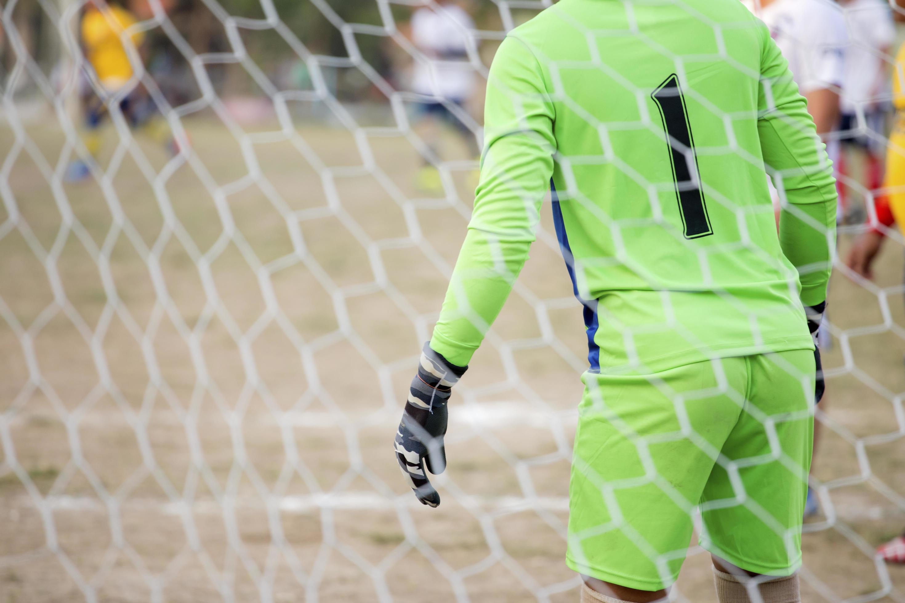 Goalkeeper stands against goal with net and stadium. Football gate net. Behind goal of soccer