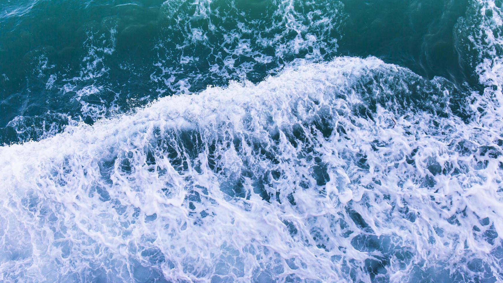 Top view with waves and bubbles of ocean blue water surface. photo