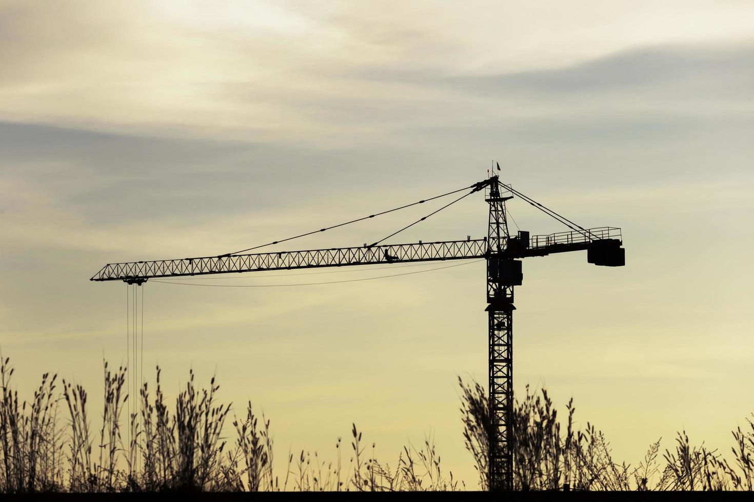 grúas de construcción industrial y siluetas de edificios sobre el sol al amanecer foto