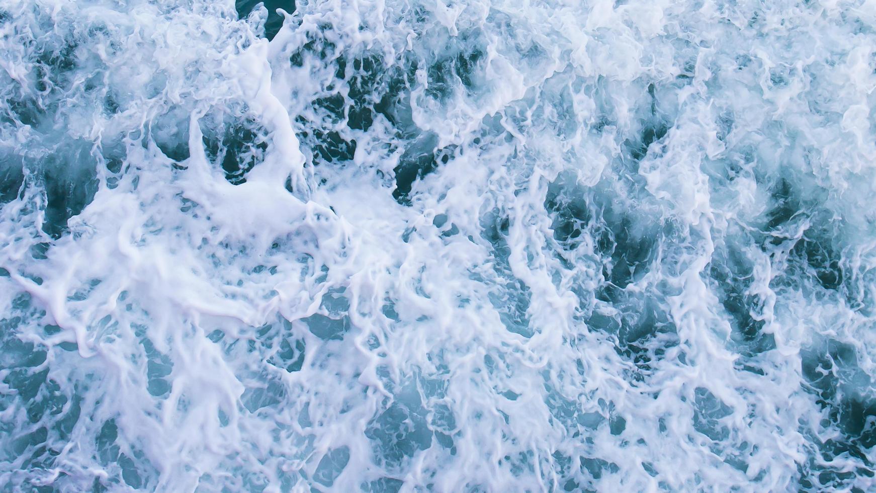 vista superior con olas y burbujas de la superficie del agua azul del océano. foto