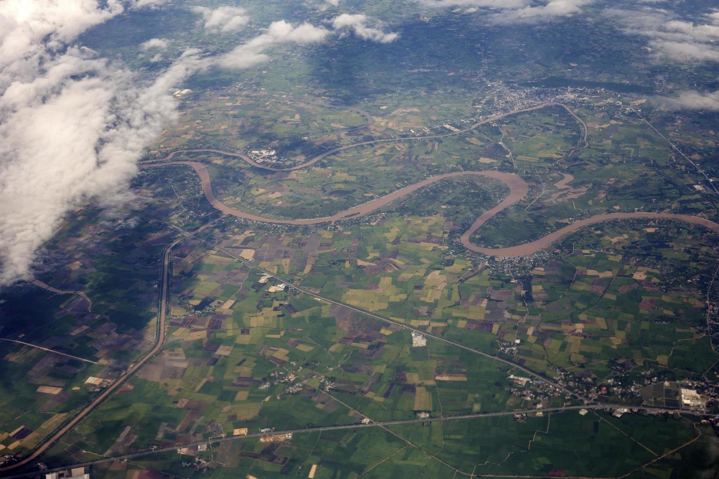 aerial photo from window of plane, above ground and cloud, green field under the clouds