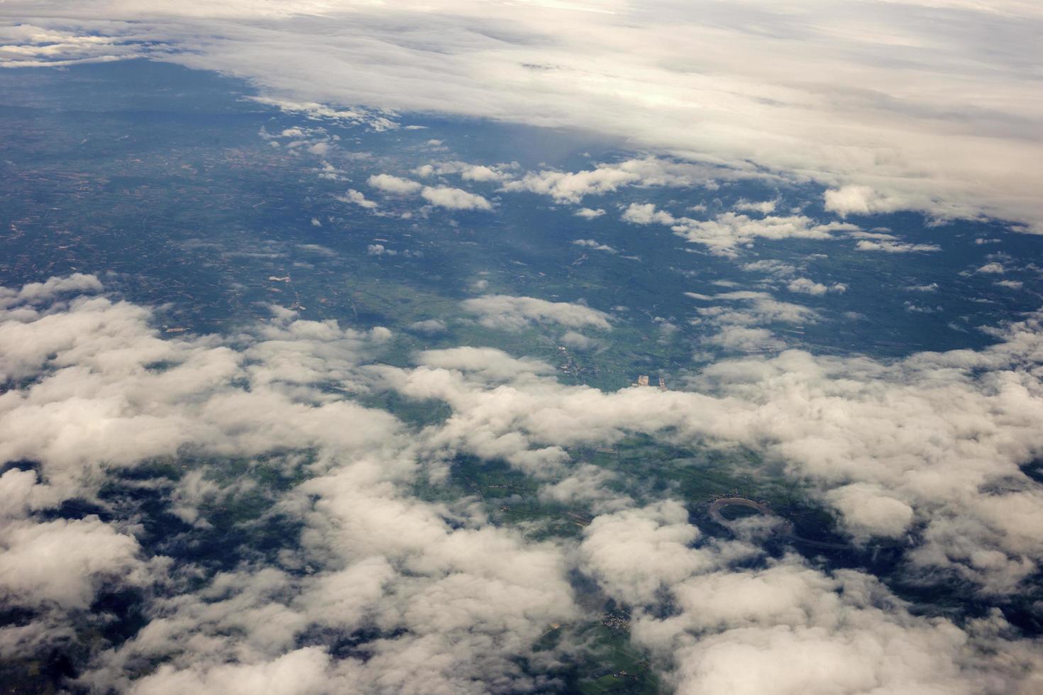 aerial photo from window of plane, above ground and cloud, green field under the clouds