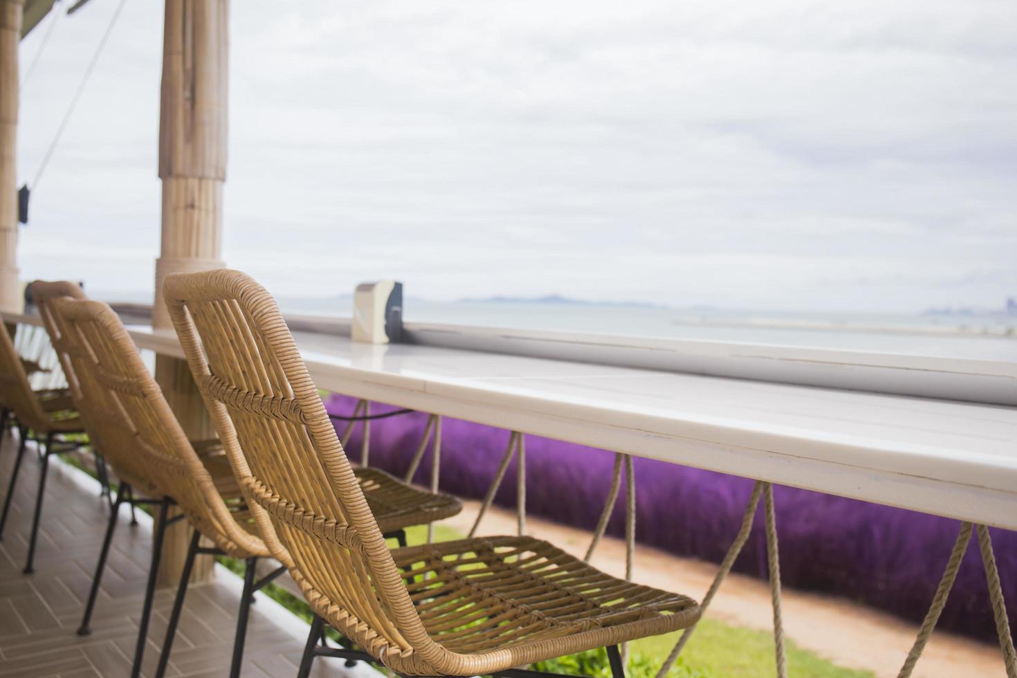 Rattan chairs line the balcony by the sea. photo