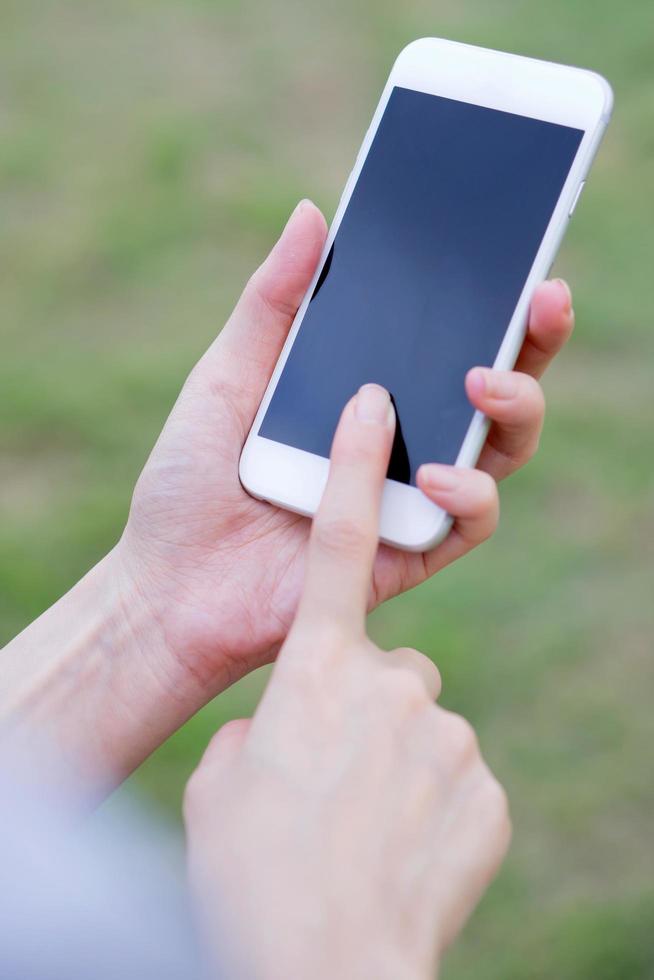 Closeup of female hand using a mobile phone on farm background photo