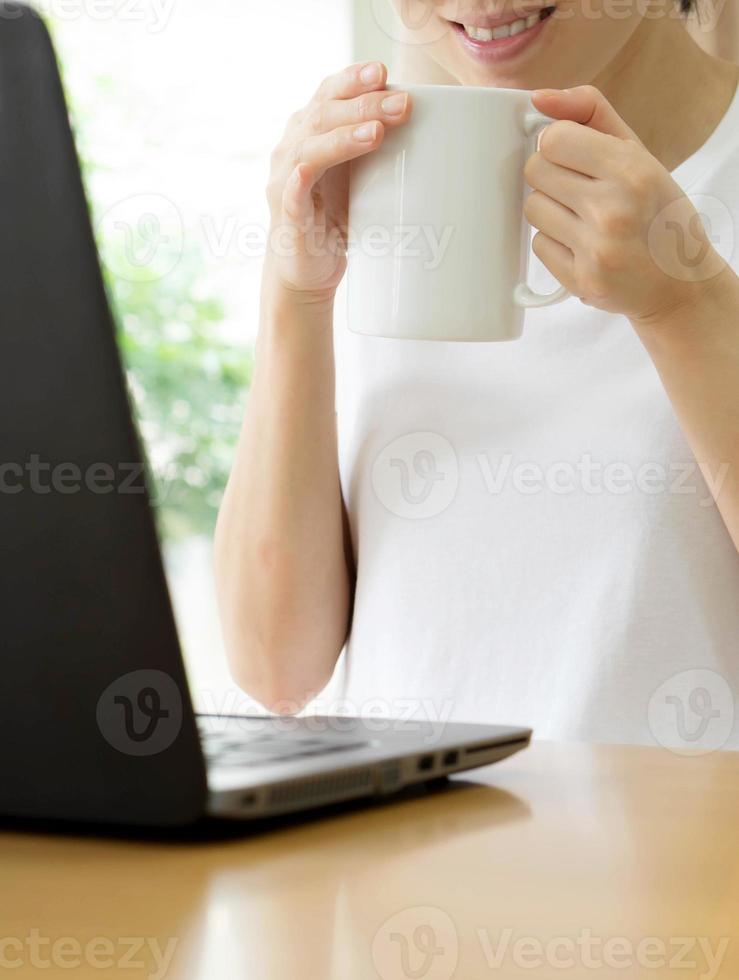 joven empresaria tomando café y usando una laptop foto