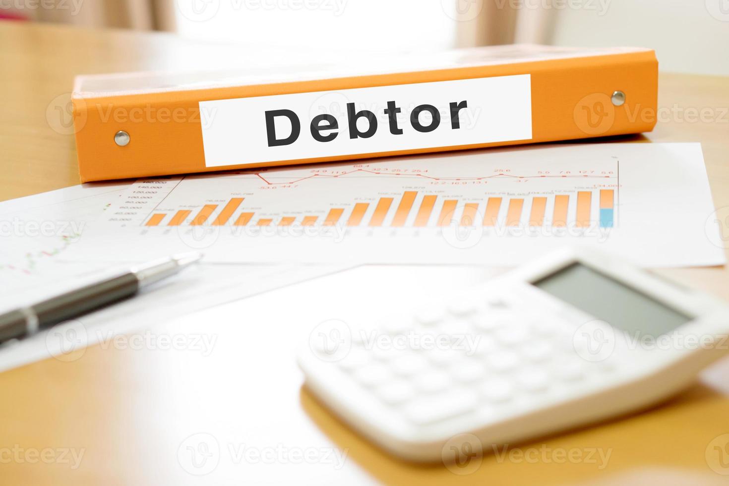 Orange  binder debtor on desk in the office with calculator and pen photo