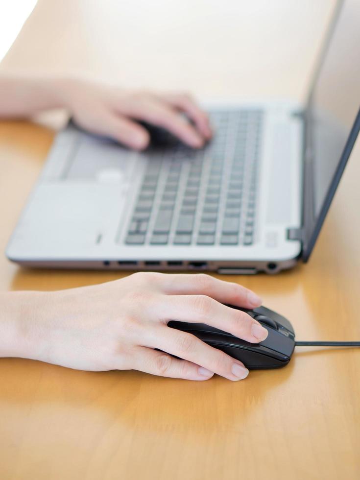 mano femenina con ratón de computadora en la mesa, primer plano foto