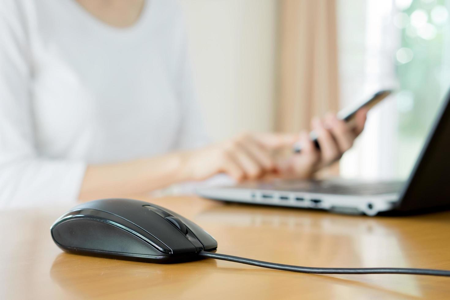 mujer joven ocupada está escribiendo en la computadora portátil y utilizando el teléfono móvil al mismo tiempo foto