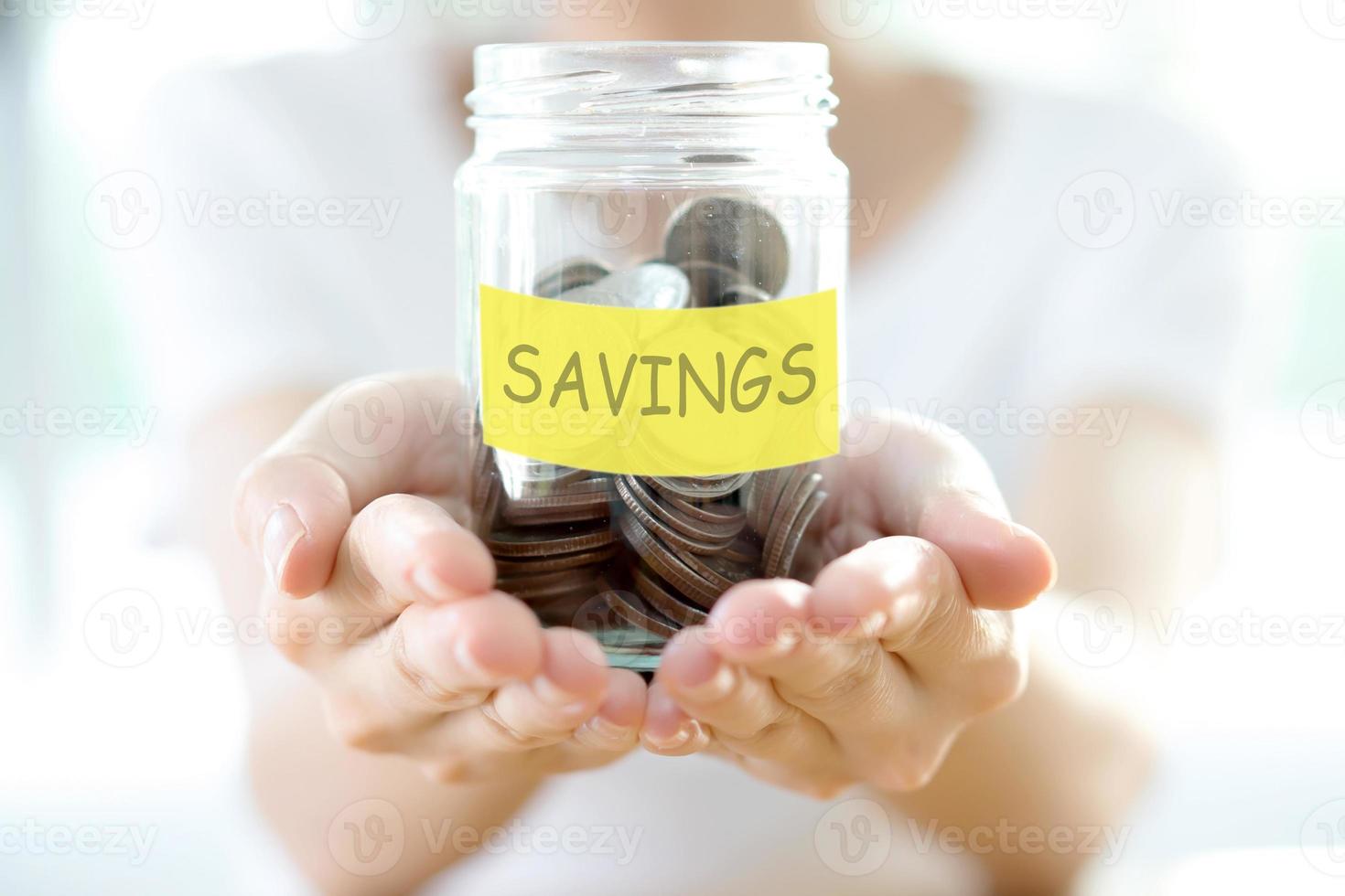 Woman holding money jar with coins close up photo