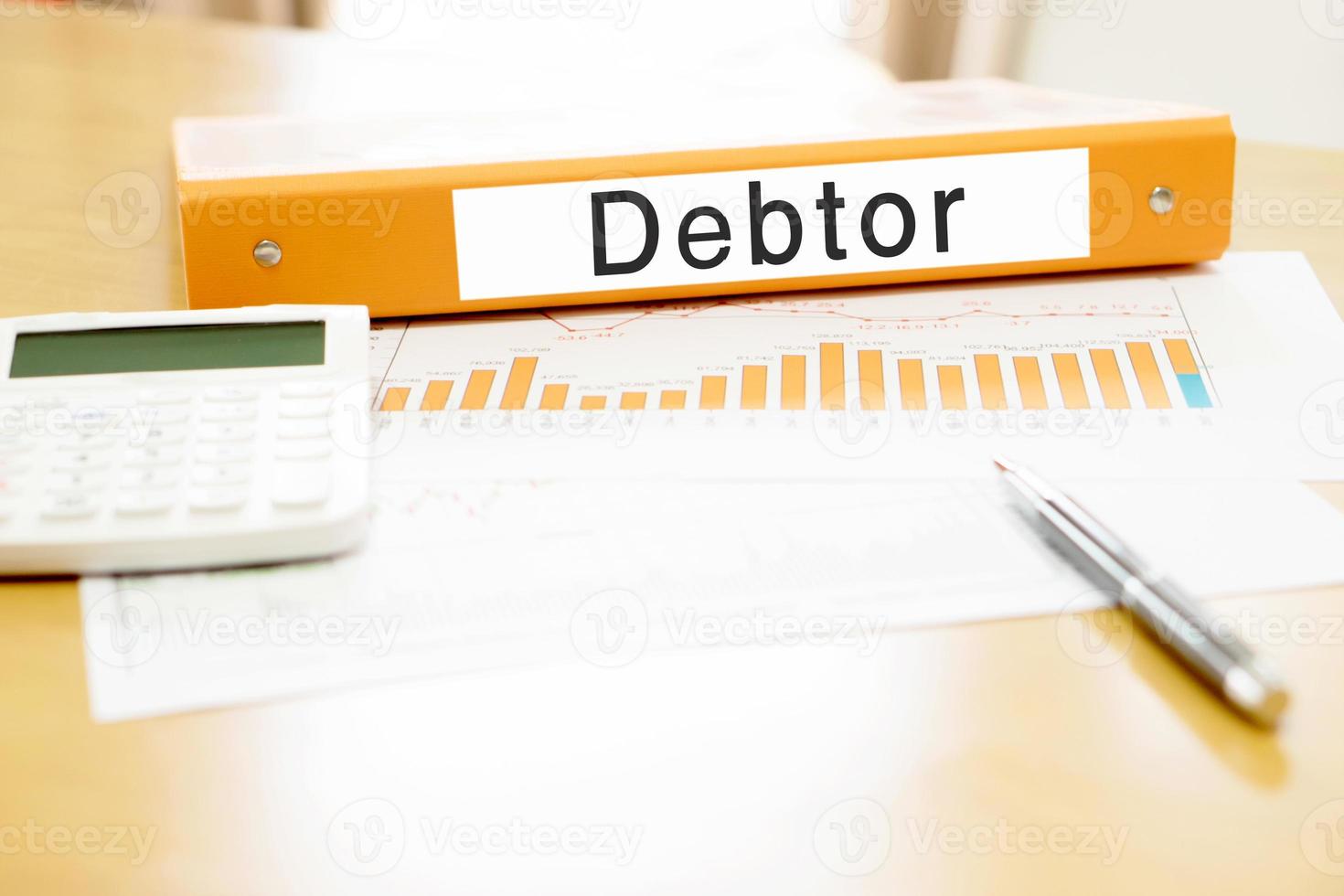 Orange  binder debtor on desk in the office with calculator and pen photo