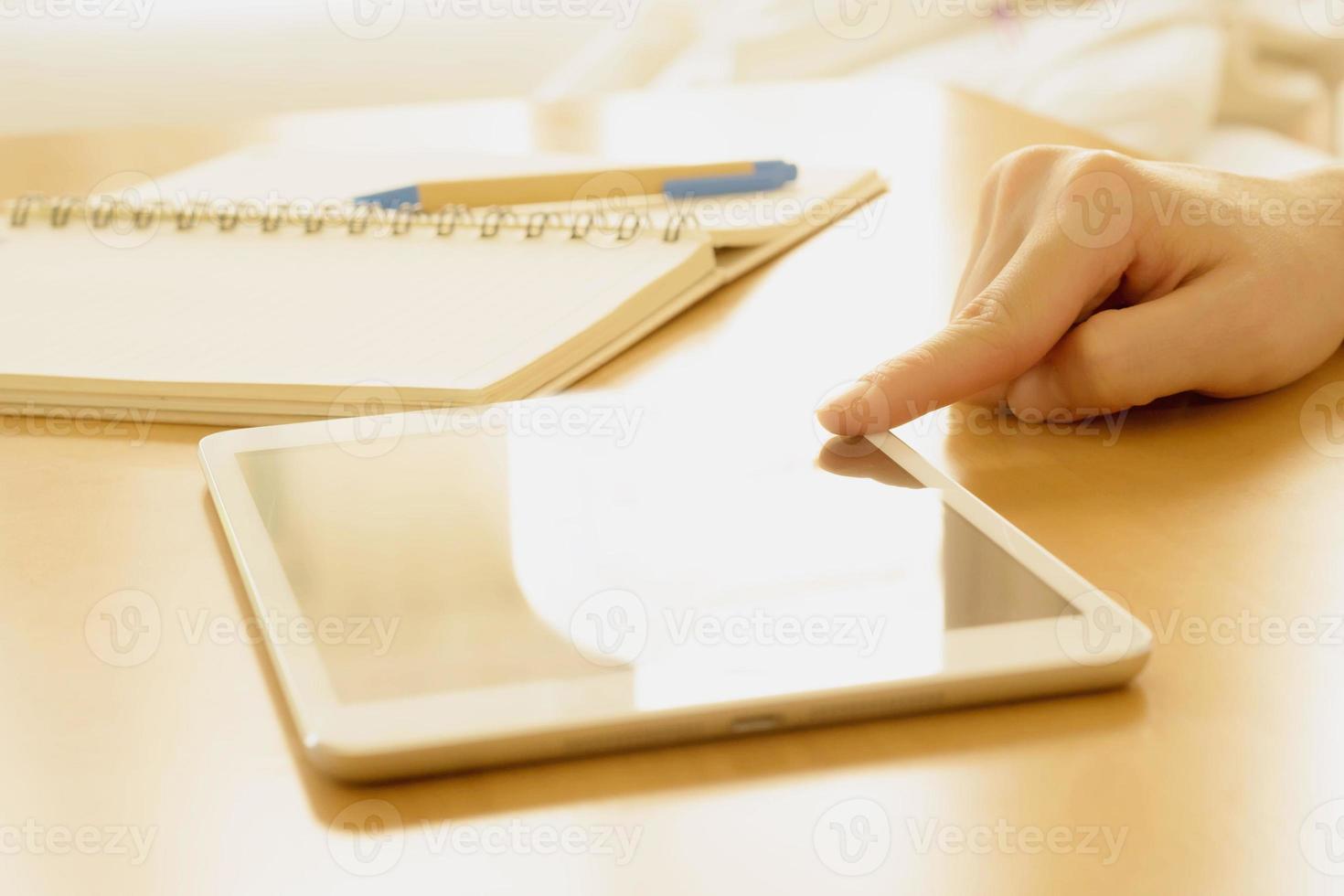 Close up of a student hand searching in a tablet on a desk at home photo