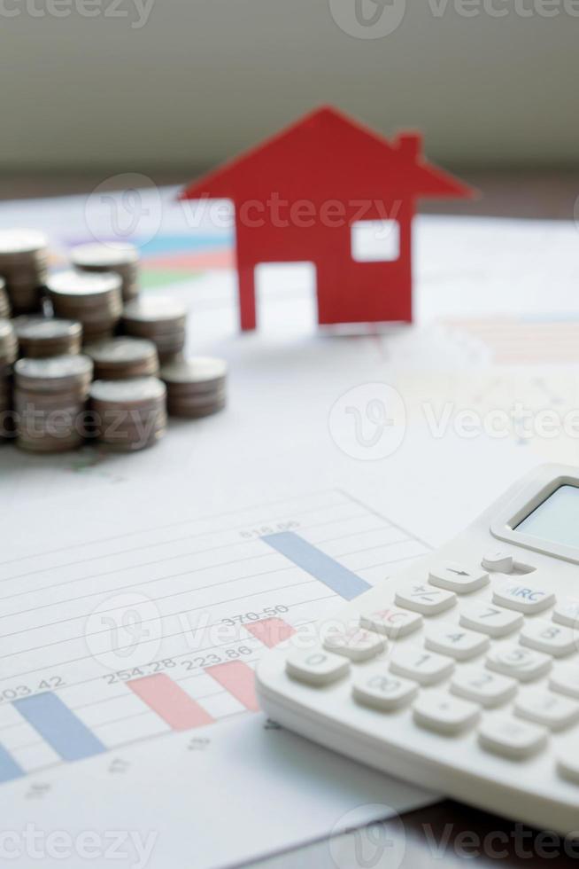 con modelo de casa y pila de monedas en el escritorio foto