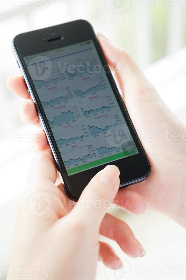 las mujeres analizan el mercado de valores usando un teléfono inteligente móvil foto