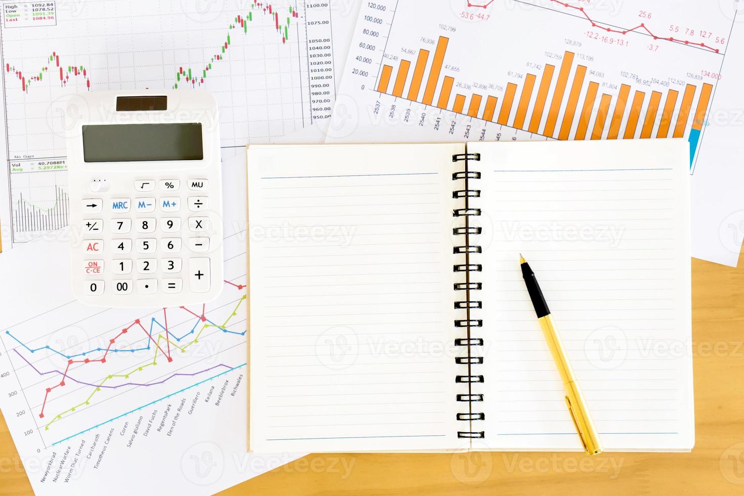 Top view workspace with booklet, pen and graphs. Wooden table background in vintage toned. photo