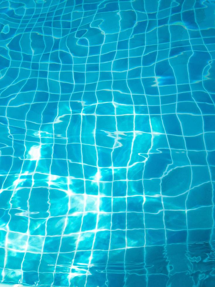 The water in the swimming pool with light reflecting the bottom of the pool is a blue checkerboard tile. photo