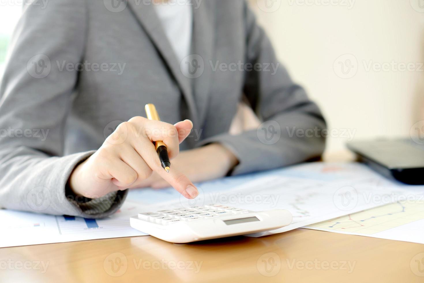 mujer de negocios analizando informe en gráfico con calculadora foto
