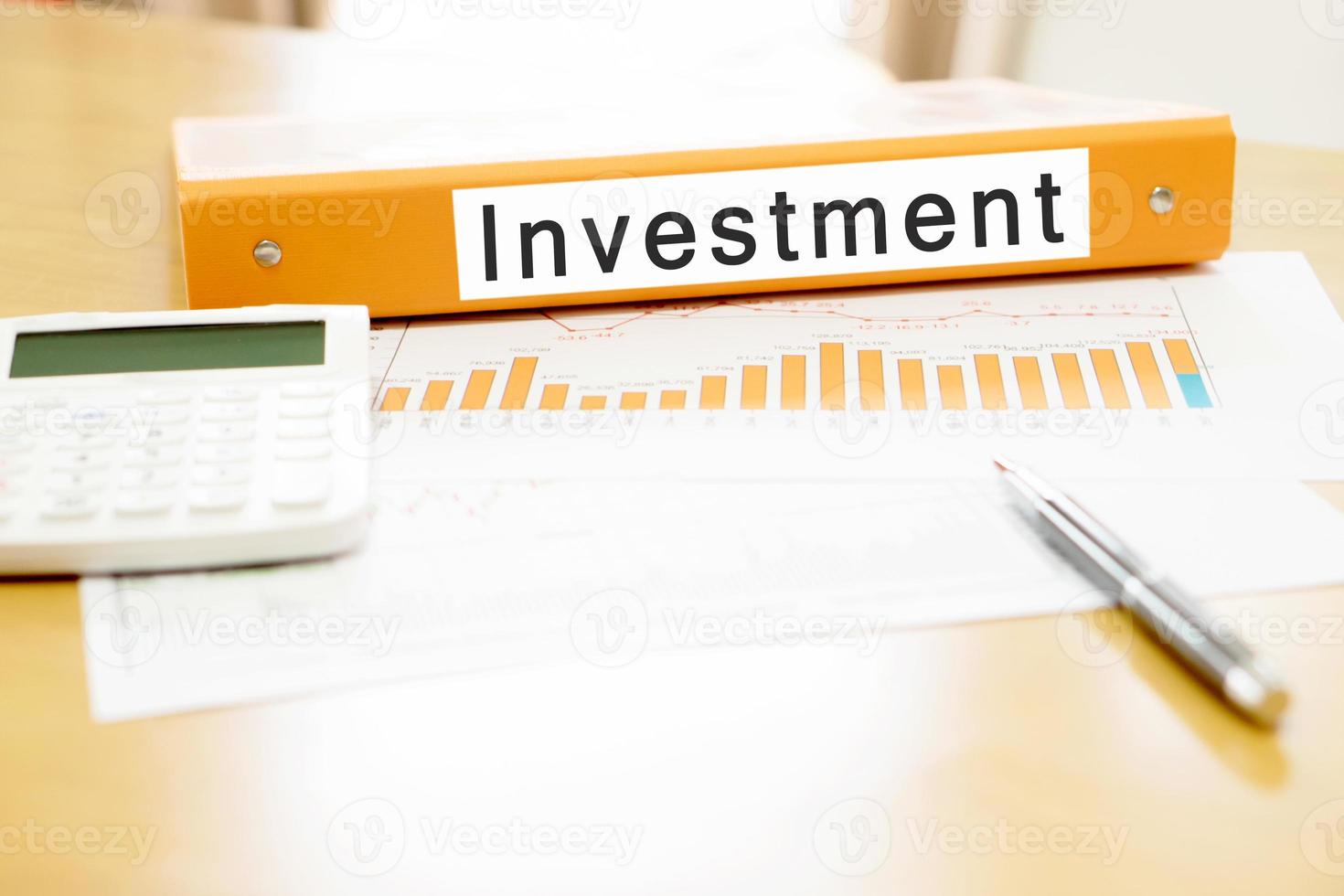 Orange  binder investment on desk in the office with calculator and pen photo