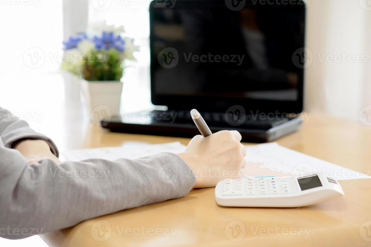 mujer joven escribe un mensaje de texto en papel y computadora portátil, calculadora foto