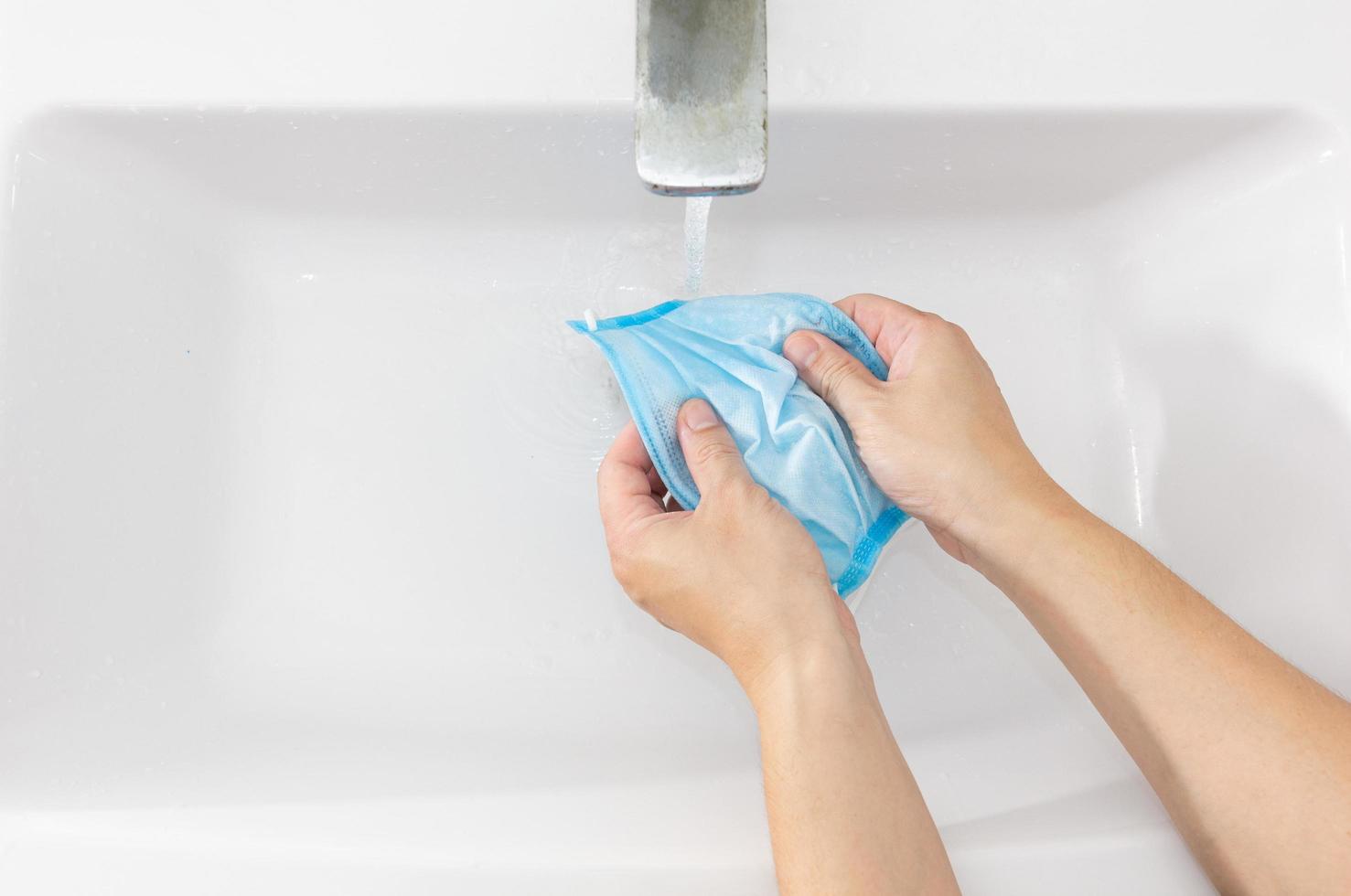 Hand of an Asian man washing a mask. Concept of cleaning a mask. photo