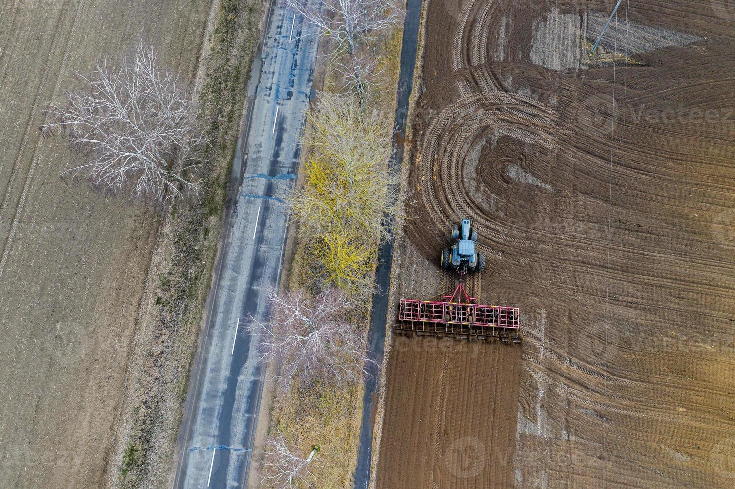 Aerial top view of a tractor, combine harvester plowing agricultural land in the spring photo