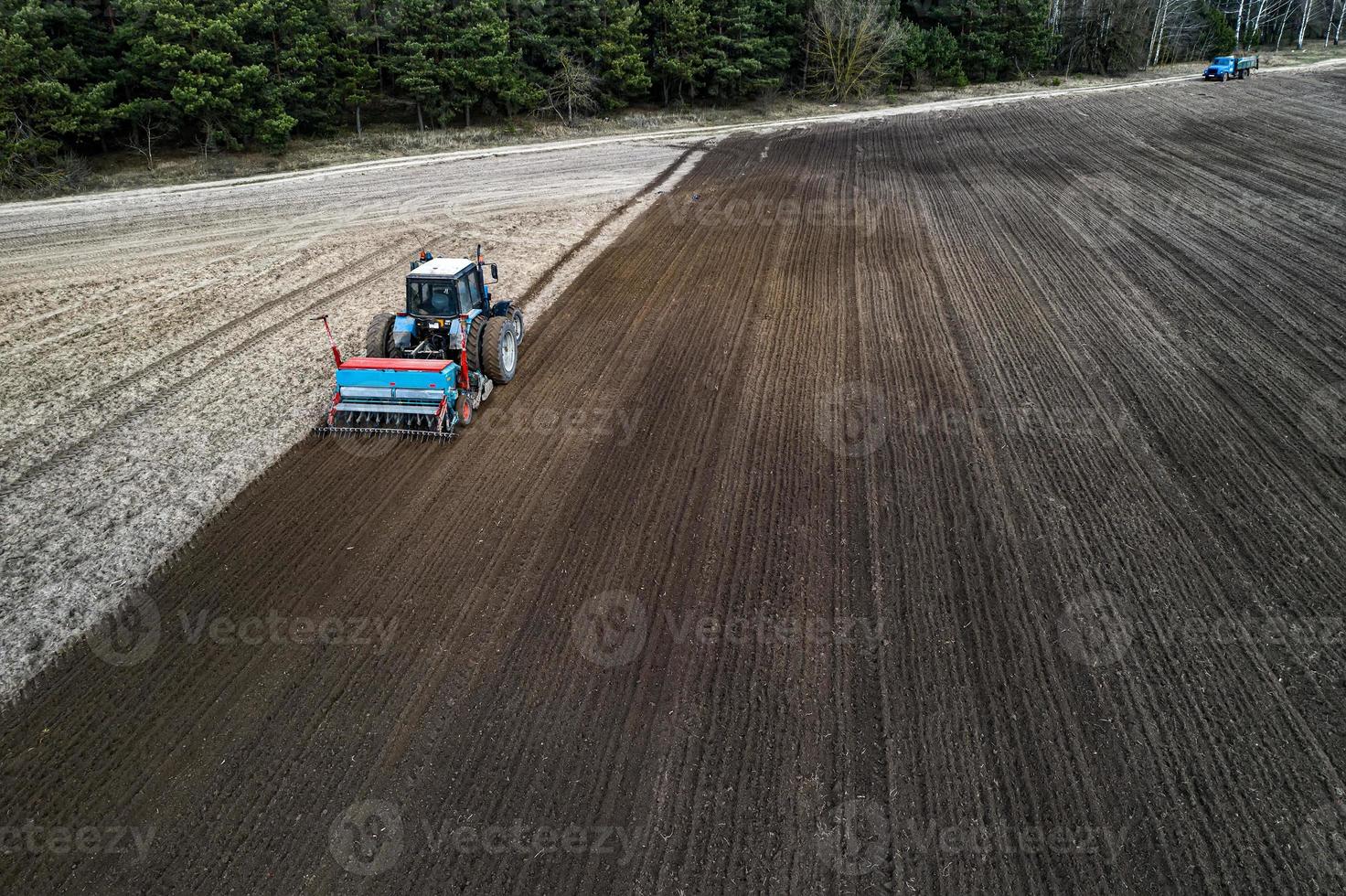 a tractor plows a field in the spring aerial view from a drone photo