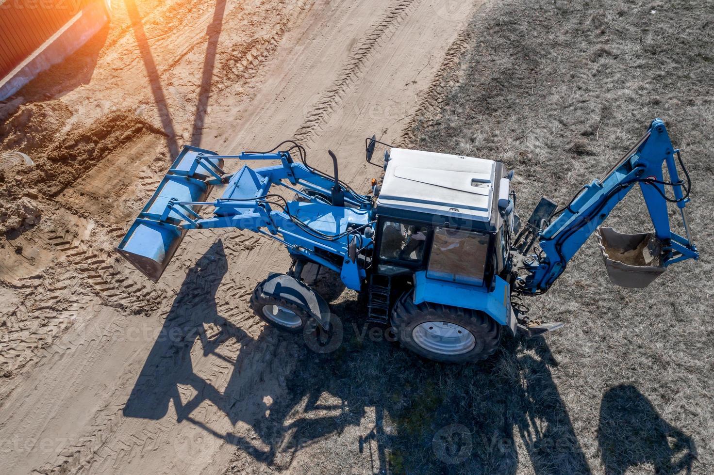blue excavator buries a hole top view photo