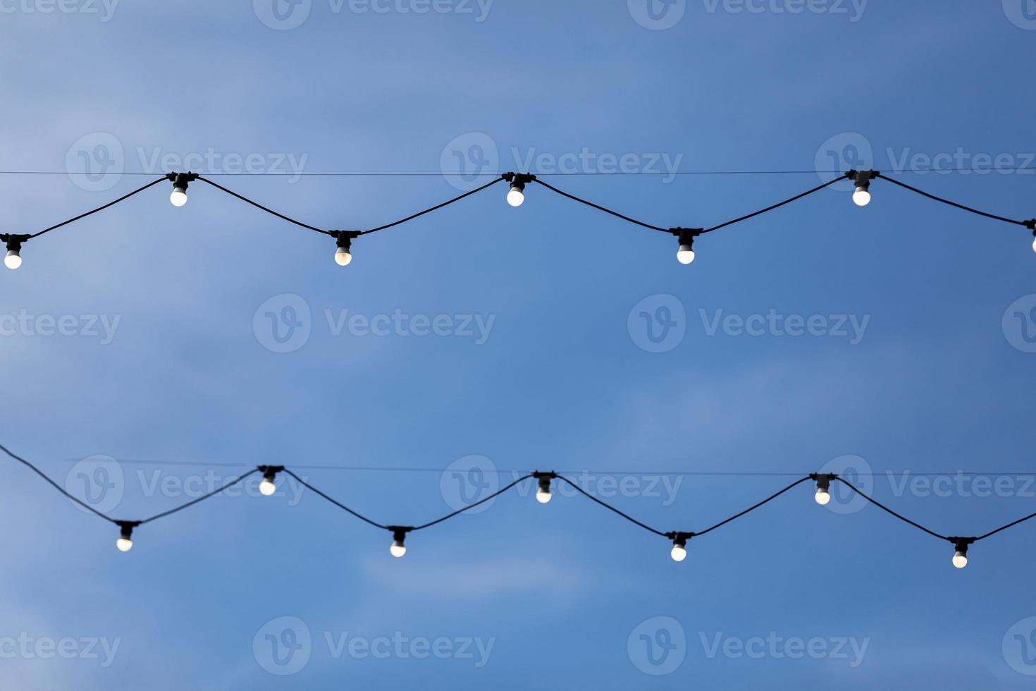 String of light bulb decoration for outdoor activities like party, concert, festival, fun fair etc with blue sky background. photo
