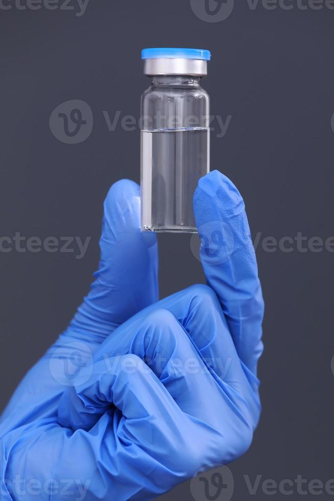 Development and creation of a coronavirus vaccine COVID-19 .Coronavirus Vaccine in glass bottle in hand of doctor on gray background. Vaccine Concept of fight against coronavirus. photo