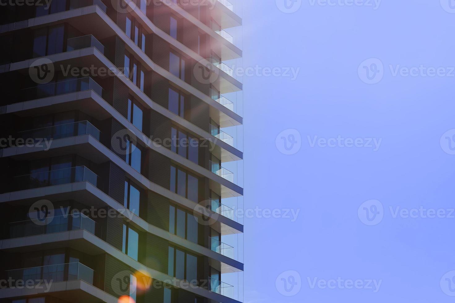 Fragment of modern multi-storey residential building against blue sky. Close-up. Background for ad or banner. Copy space. modern housing. sale of apartments. photo