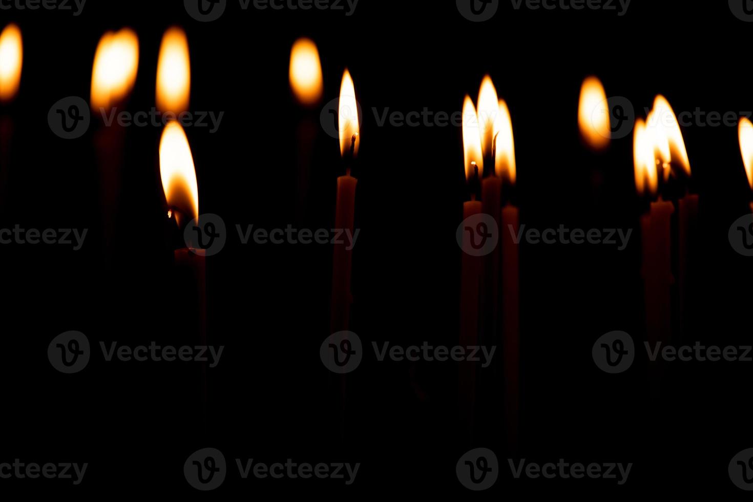 Cierra muchas velas encendidas aisladas en el fondo negro. foto