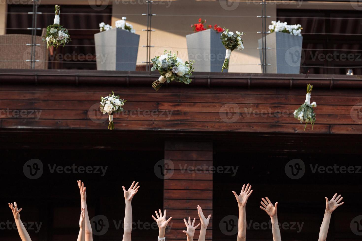 bride and bridesmaids throwing bouquets up, joyful moment. bride with girls having fun in wedding morning photo