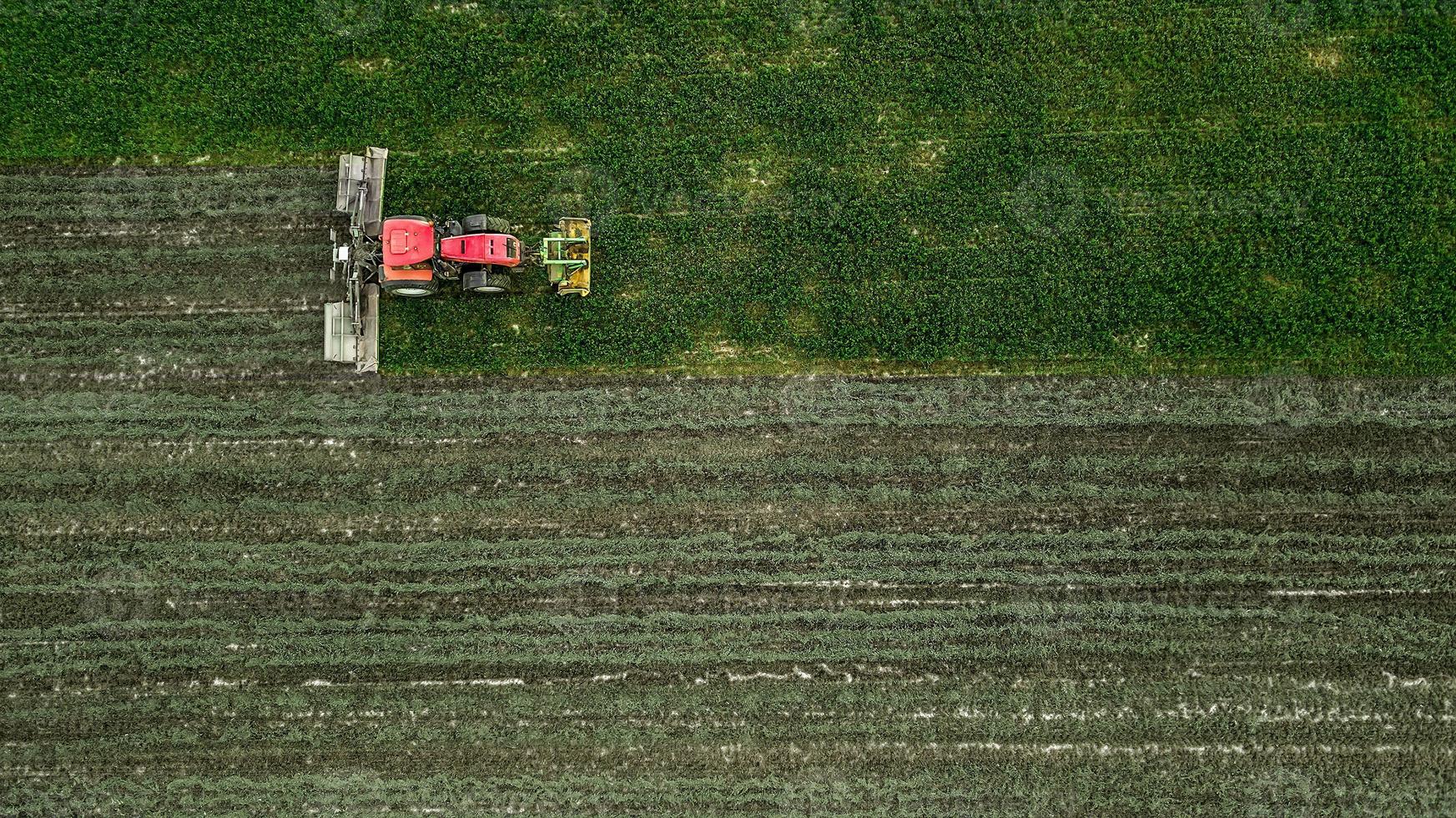 un tractor corta un campo de fotografía aérea con drones foto